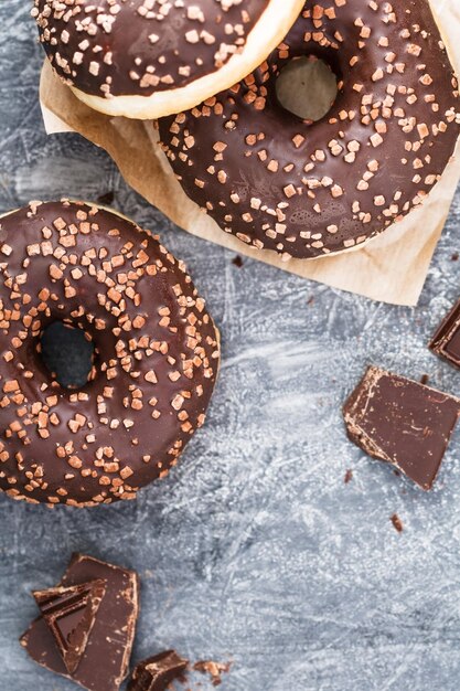 Trois beignets au chocolat sur un fond texturé gris Mise à plat Copier l'espace