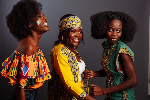 Photo trois belles jeunes mannequins africaines s'amusent et rient en costume traditionnel femmes de la république du congo côte d'ivoire et du zimbabwe