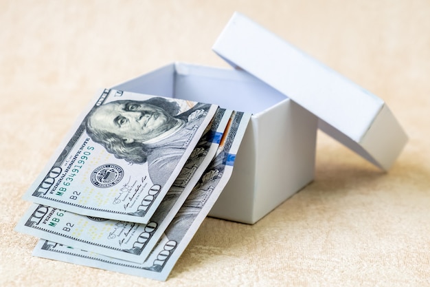 Photo trois billets en dollars américains de 100 dollars dans une boîte cadeau blanche. prise de vue en studio.