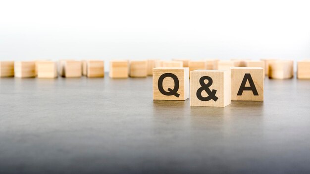 Trois blocs de bois avec des lettres Q et A en mettant l'accent sur le cube unique au premier plan dans une image conceptuelle sur fond gris