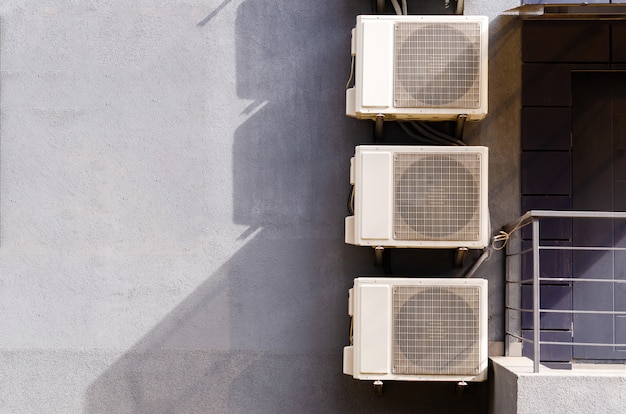 Trois blocs (boîtes) de climatisation à l'avant du bâtiment.