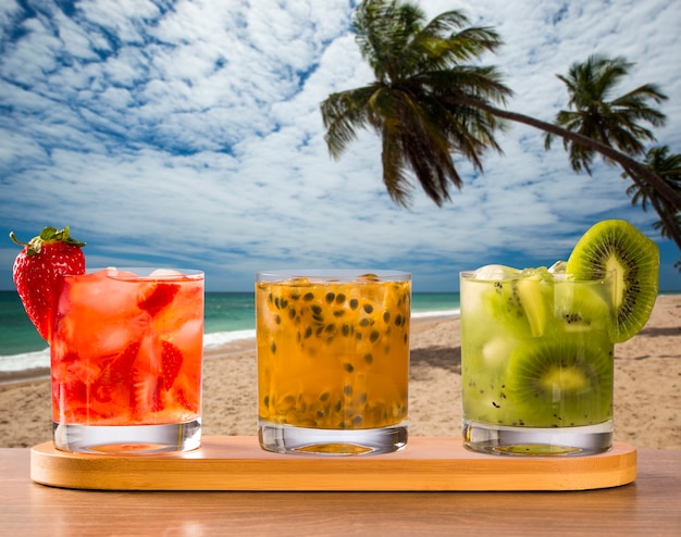 Trois boissons à base de fruits de la passion, fraise et kiwi Caipirinha dans le fond de la plage