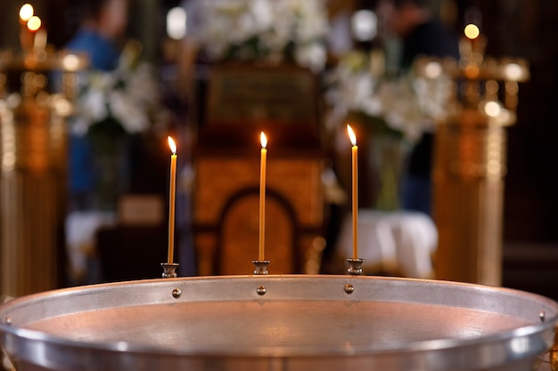 Trois bougies allumées sur un font pour le baptême dans une église