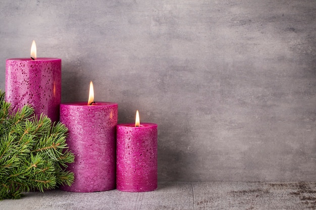 Trois bougies violettes sur fond gris, décoration de Noël. Humeur de l'Avent.