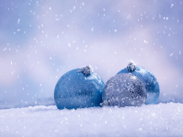 Trois boules de Noël sur la neige scintillante. flocons de neige tombant.