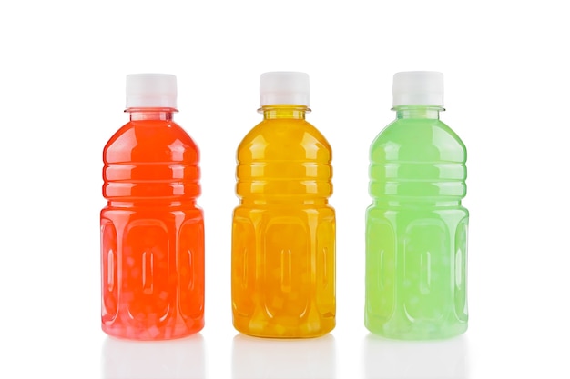 Trois bouteilles en plastique avec boisson aux fruits de différentes couleurs isolées sur blanc