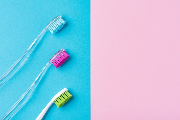 Trois brosses à dents en plastique sur un bleu et rose coloré