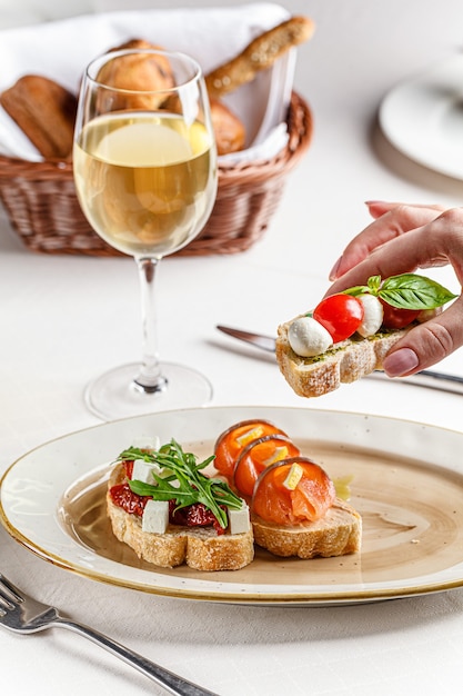 Trois bruschettas italiennes sur une plaque blanche avec fromage, tomates cerises