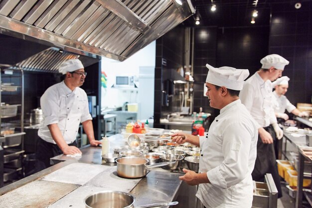 trois chefs sous la forme, dans la cuisine, préparer des plats à l'aide de couverts