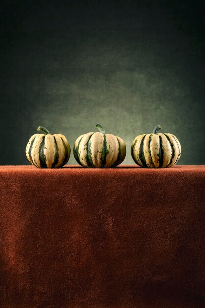 Trois citrouilles décoratives à rayures sur une table marron