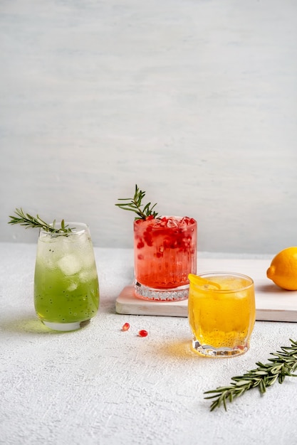 Trois cocktails d'été colorés dans des verres sur un tableau blanc.