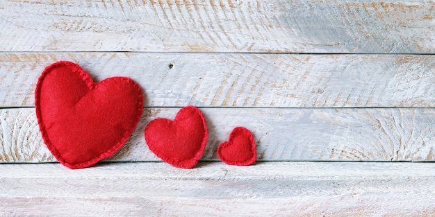 Trois coeurs de feutre rouge sur des planches en bois, concept de famille, amour