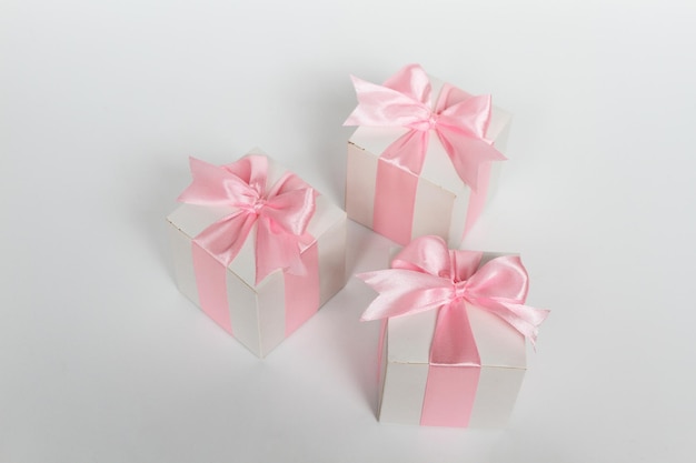 Trois coffrets cadeaux avec ruban de satin rose isolé sur fond blanc