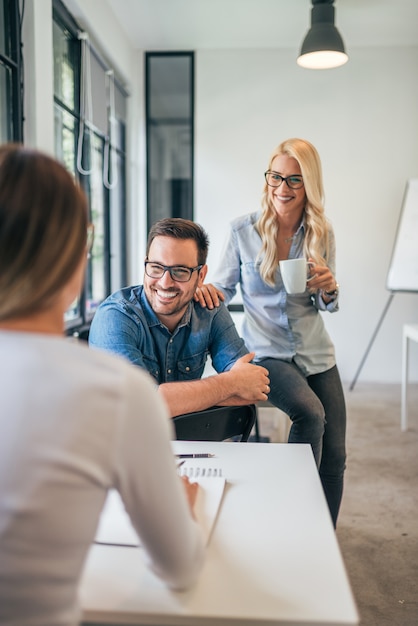 Trois Collègues Dans Un Espace De Coworking Ou Une Salle De Classe Moderne Parlant Et Souriant.