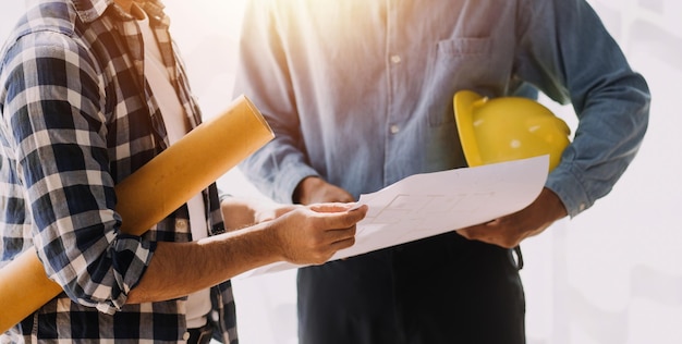 Trois collègues discutant du travail des données et de l'ordinateur portable avec une tablette sur un projet architectural sur un chantier de construction au bureau au bureau