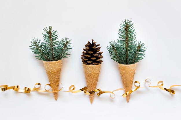 Photo trois cônes de gaufres avec des branches de sapin et cône et ruban d'or