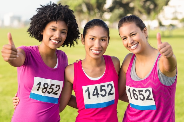 Trois coureurs souriants soutenant le marathon du cancer du sein