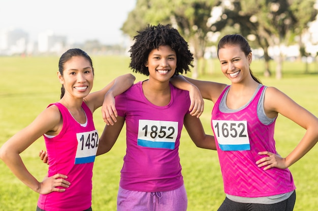 Trois coureurs souriants soutenant le marathon du cancer du sein