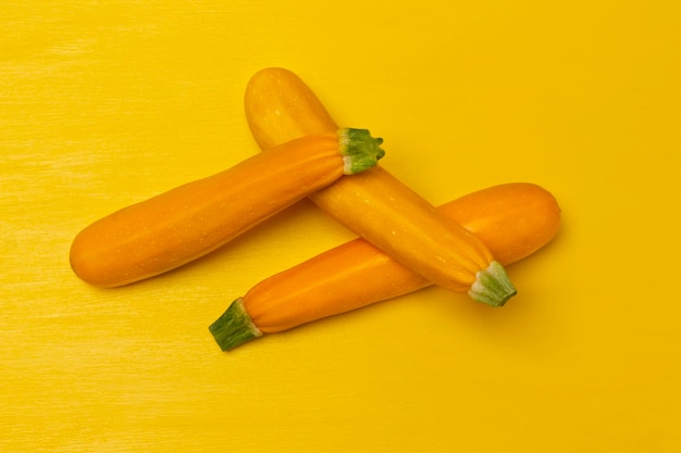 Trois courgettes jaunes sur fond jaune