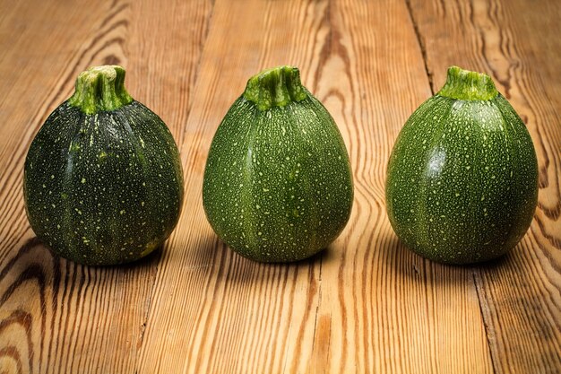 Trois courgettes rondes sur une table en bois