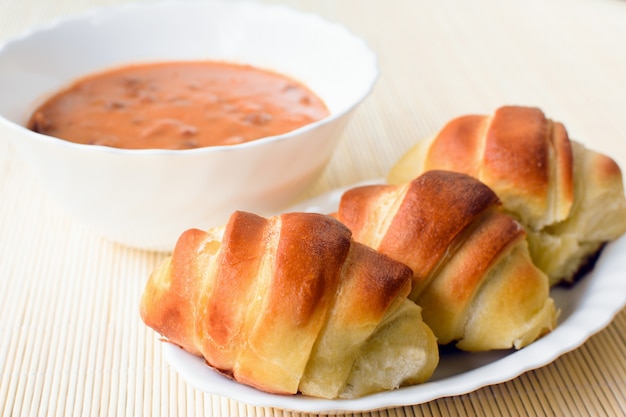 Trois croissants et un bol de haricots sur fond clair