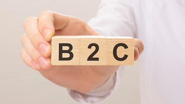 Trois cubes en bois avec les lettres B2C sur la main sur le fond blanc b2c est l'abréviation d'entreprise à consommateur