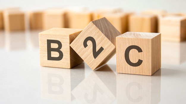 Trois cubes en bois avec les lettres B2C sur la surface lumineuse d'une table grise, concept d'entreprise