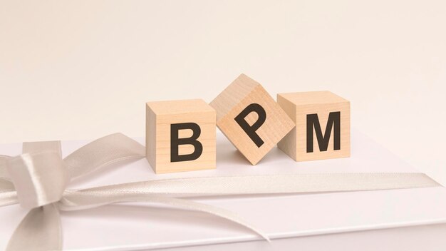 Trois cubes avec du texte BPM sur la surface blanche d'une boîte-cadeau attachée avec un fond blanc de ruban festif léger BPM court pour Business Process Management