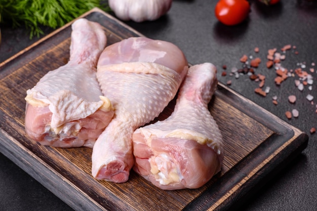 Trois cuisses de poulet cru aux épices et herbes sur une planche à découper en bois