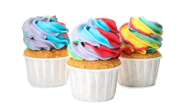 Trois délicieux petits gâteaux avec de la crème colorée sur fond blanc