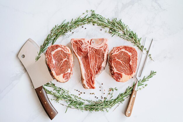 Trois délicieux steaks prêts à griller sur une surface en marbre blanc