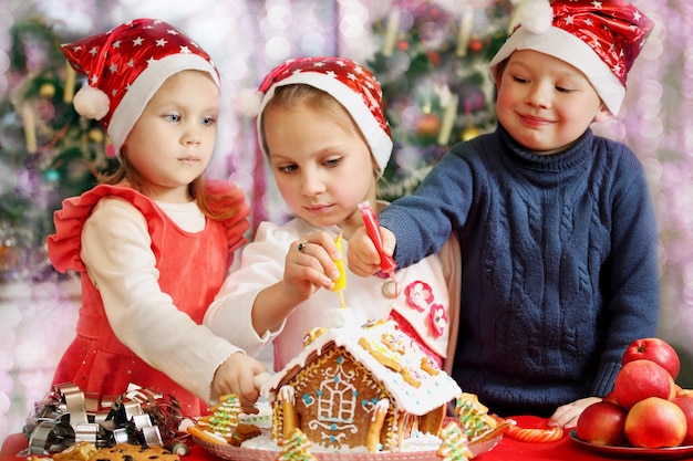 Trois enfants en casquettes décorées maison en pain d'épice