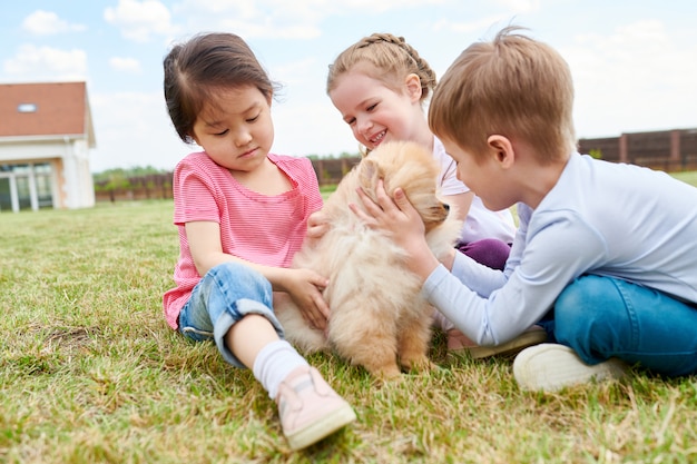 Photo trois enfants jouant avec chiot