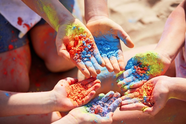 Trois enfants tenant de la poudre colorée dans les mains