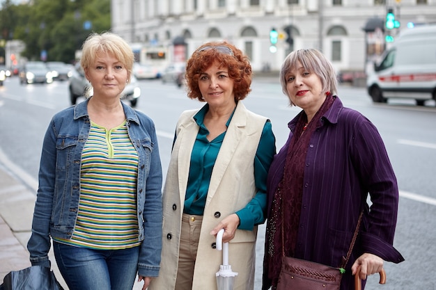 Trois femmes d'âge moyen de race blanche en tissu décontracté sont debout sur la rue de la ville pendant la marche.