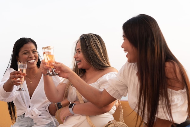 Trois femmes assises portant un toast avec des verres de vin lors d'une fête