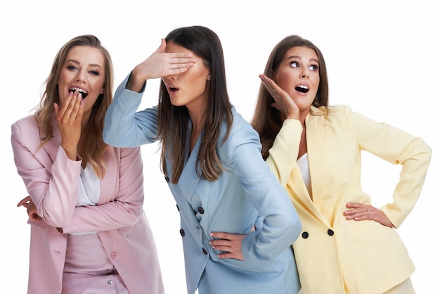 Trois femmes en costumes pastel posant sur fond blanc