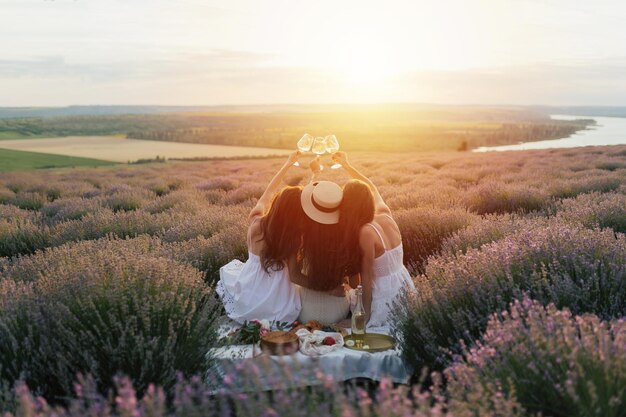 Trois femmes dans un champ de lavande avec des verres de vin