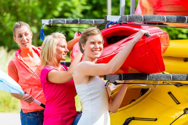 Trois femmes déchargeant un kayak de remorque à bateau