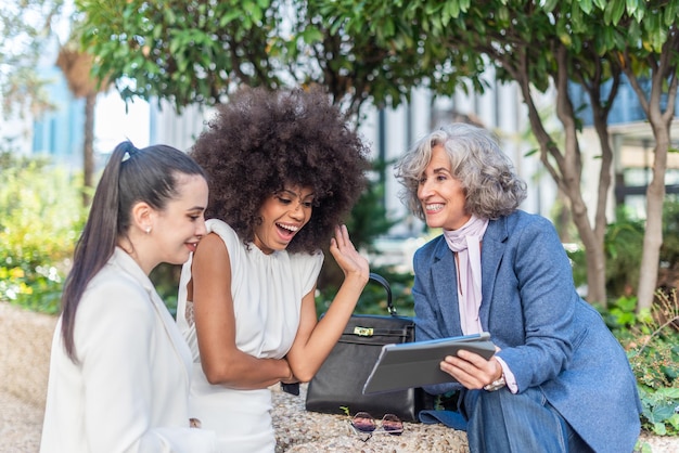 Trois femmes entrepreneurs s'amusant à regarder quelque chose sur la tablette, vue rapprochée