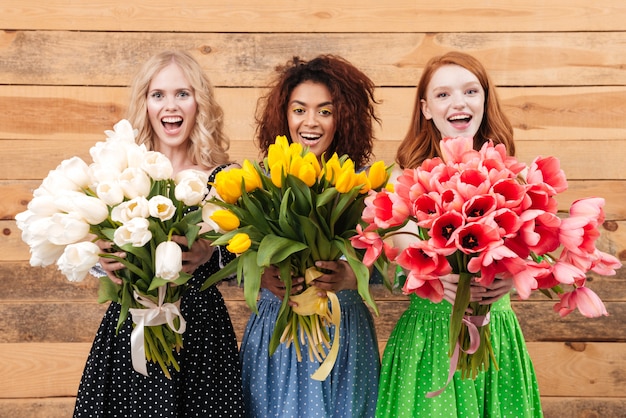 Trois femmes montrant des bouquets de fleurs à la caméra