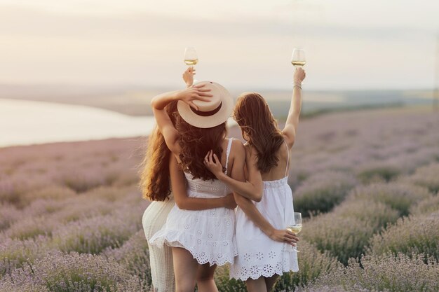 Trois femmes en robes blanches se tiennent debout dans un champ de lavande.