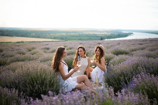 Trois femmes s'assoient dans un champ de lavande au pique-nique d'été