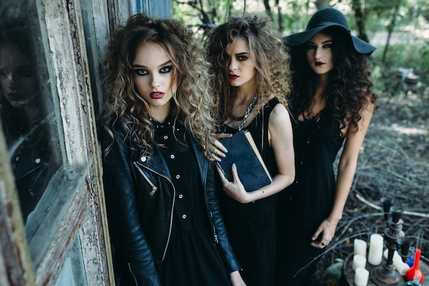 Trois femmes vintage comme sorcières, pose près d'un bâtiment abandonné à la veille d'Halloween