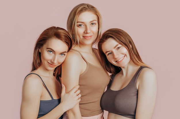 Trois filles dans des vêtements confortables à la maison ensemble sur un mur rose