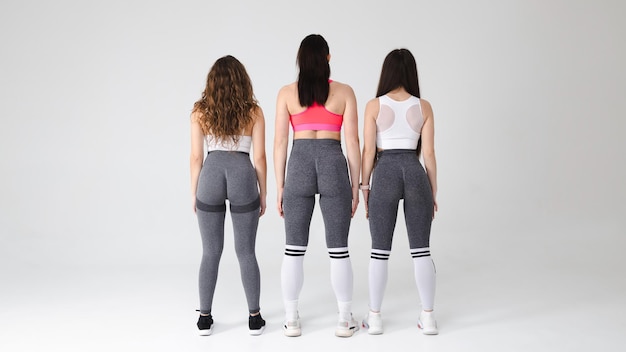 Trois filles de fitness se tiennent debout avec de belles fesses