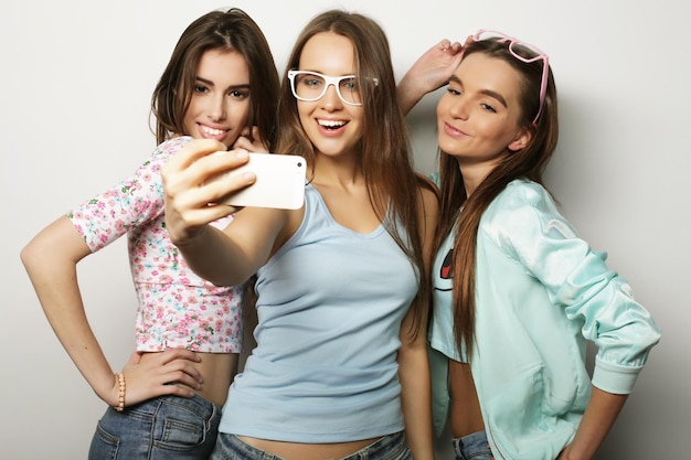Trois filles hipster adolescentes heureuses avec smartphone prenant selfie