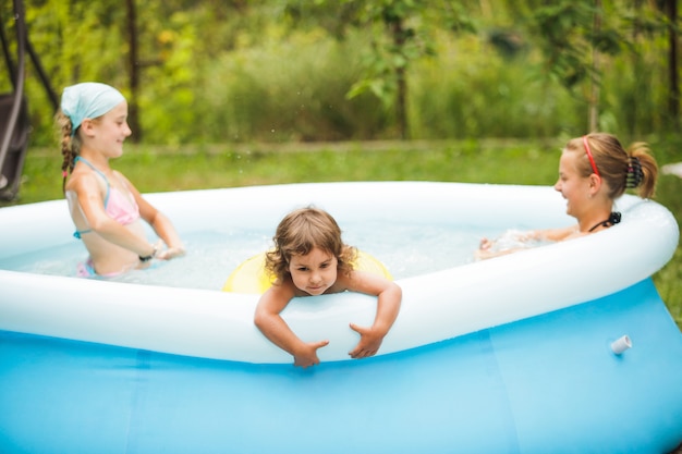 Trois filles nagent dans la piscine bleue et jouent avec le ballon