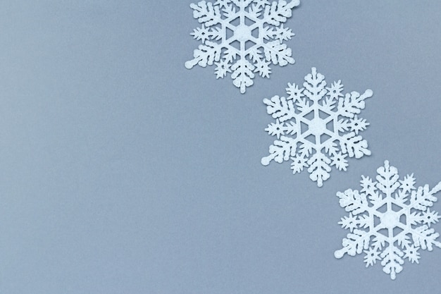 Trois flocons de neige décoratifs blancs sur fond gris. Noël et nouvel an, une place pour le texte, le minimalisme, le fond d'hiver