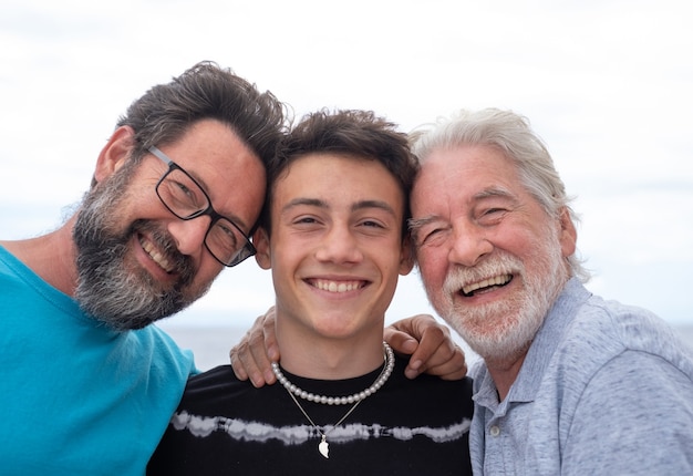 Trois générations de famille, câlin souriant heureux, père, fils adolescent et grand-père. De belles personnes s'amusant ensemble